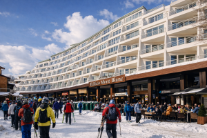 Edificio Mont Blanc en Plaza Pradollano, Sierra Nevada, con esquiadores caminando por la nieve y terrazas animadas en un día soleado de invierno